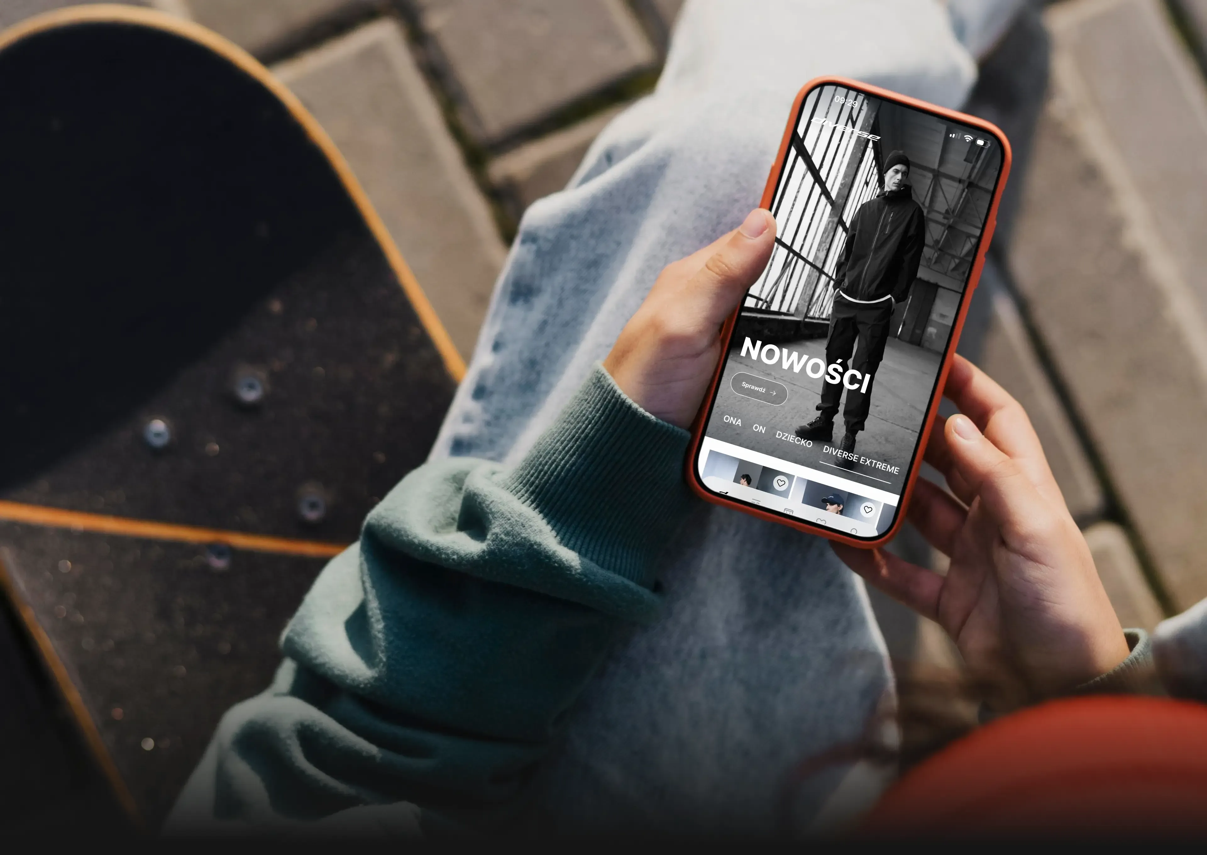 Streetwear lifestyle hand holding orange cased iPhone with skateboard in background