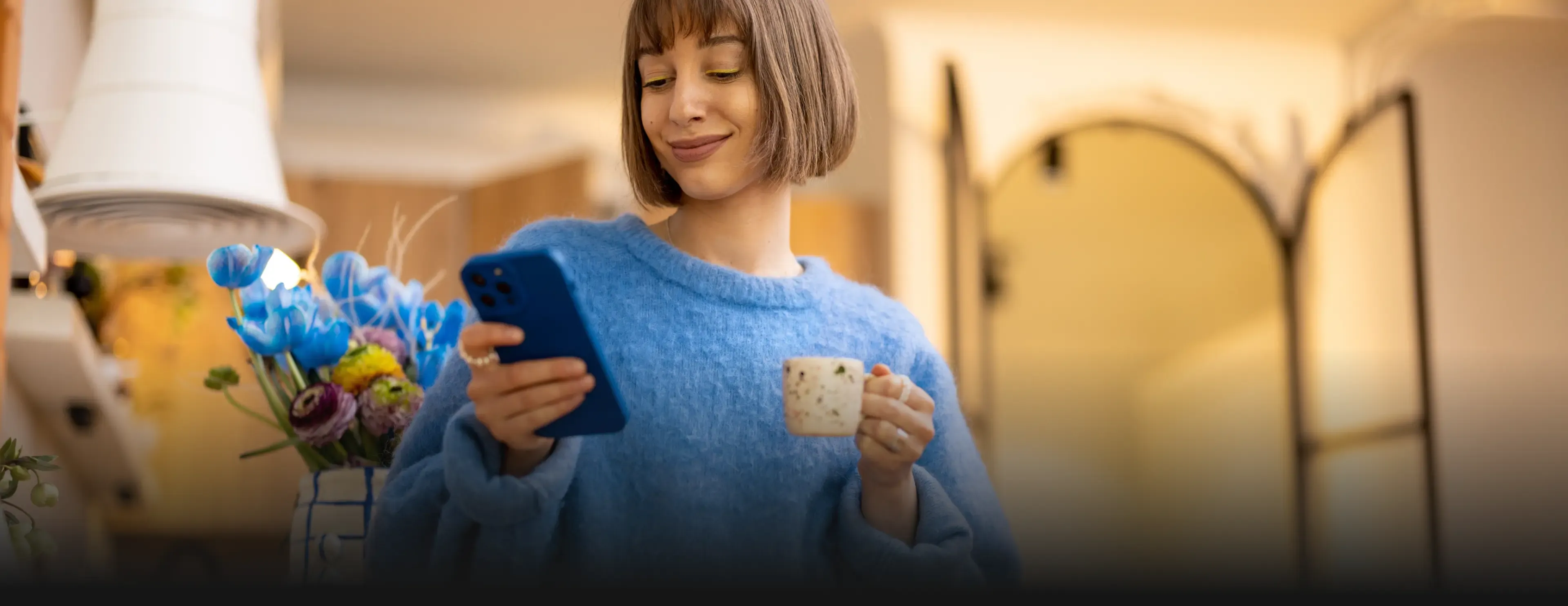 Woman in a blue sweater with a phone and mug. PEPCO logo over a cozy kitchen scene